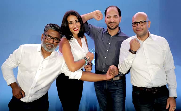 Four people stand together holding up their fists.